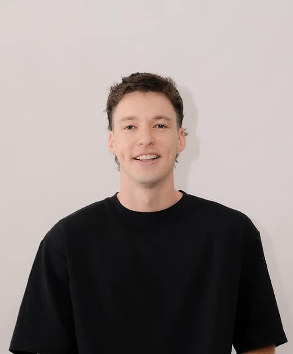 Male team member smiling, wearing a black t-shirt