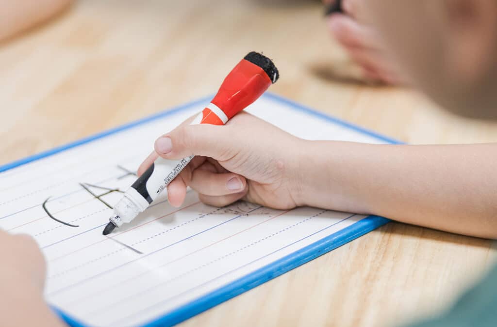 Child writing with a thick marker during a guided literacy activity